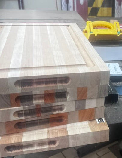 Wooden cutting boards on a table with tools and equipment in the background