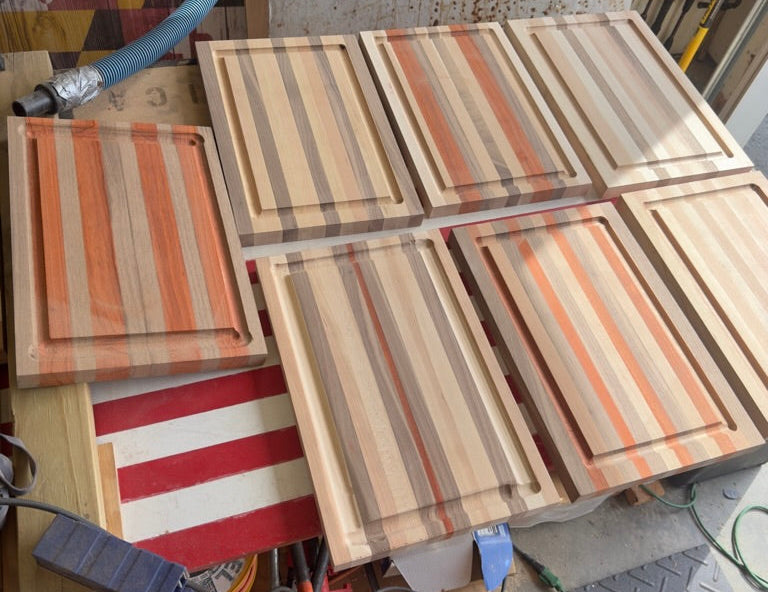 Wooden cutting boards with striped patterns on a workshop floor.