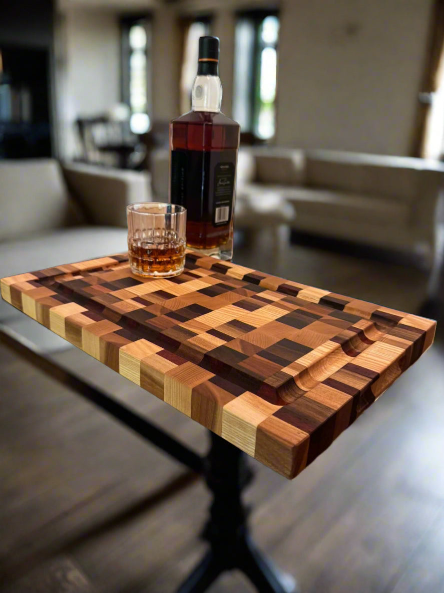 Wooden cutting board with geometric pattern on a wooden surface, accompanied by a bottle of whiskey and a glass.