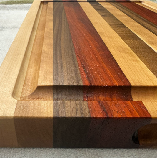 Wooden cutting board with multicolored stripes on a textured surface