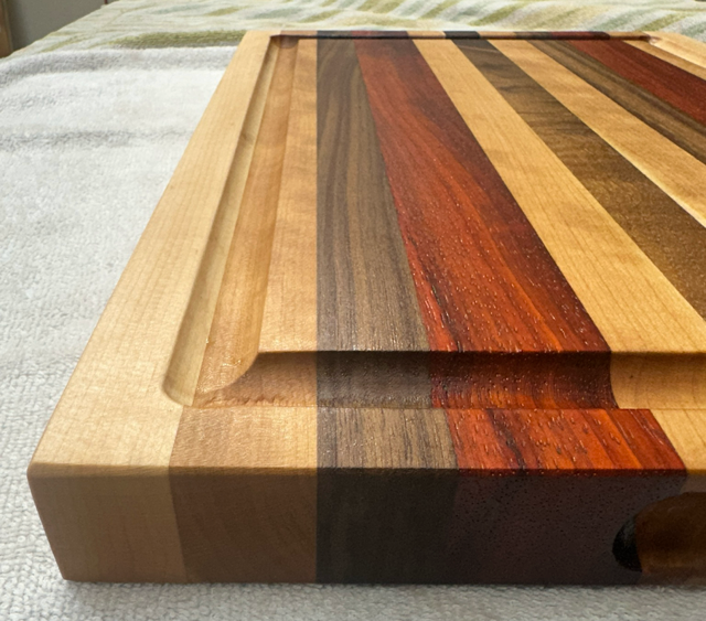 Wooden cutting board with multicolored stripes on a textured surface