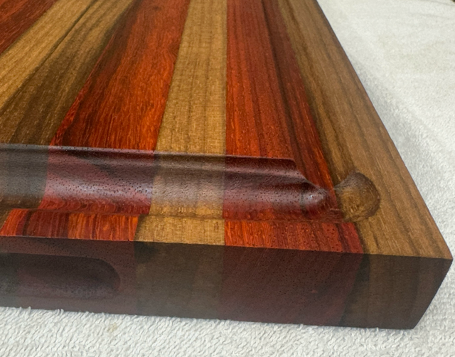 Wooden cutting board with a multicolored striped pattern on a white surface