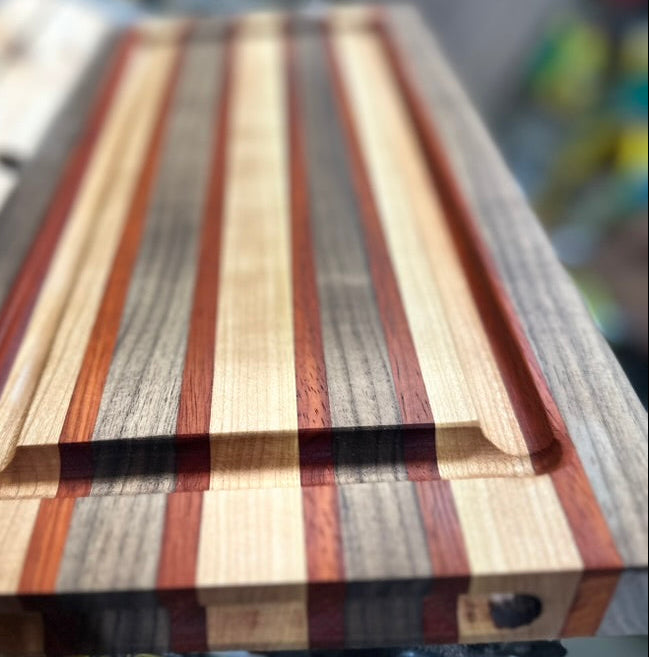 Wooden cutting board with multicolored stripes on a blurred background