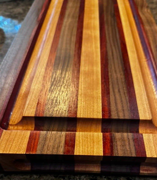 Wooden cutting board with multicolored stripes on a granite countertop
