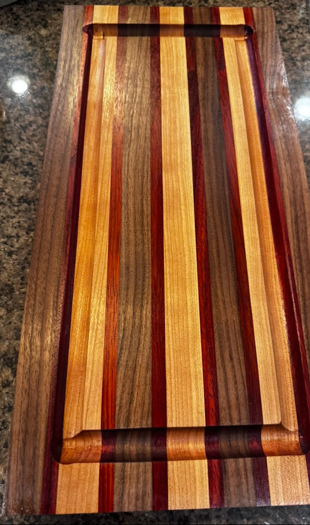 Wooden cutting board with multicolored stripes on a granite countertop