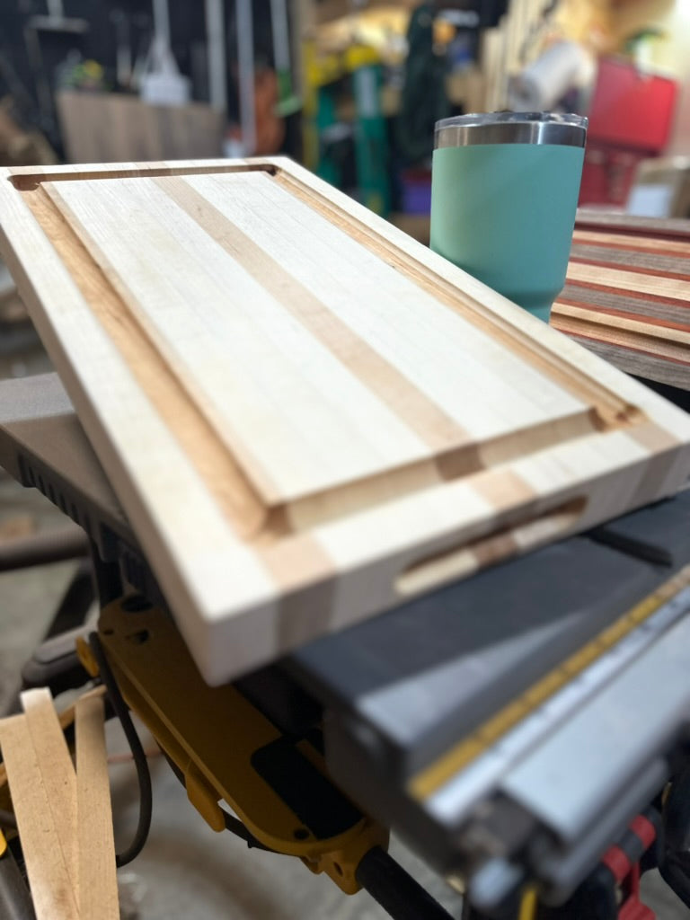 Wooden cutting board on a table saw with a teal cup in the background