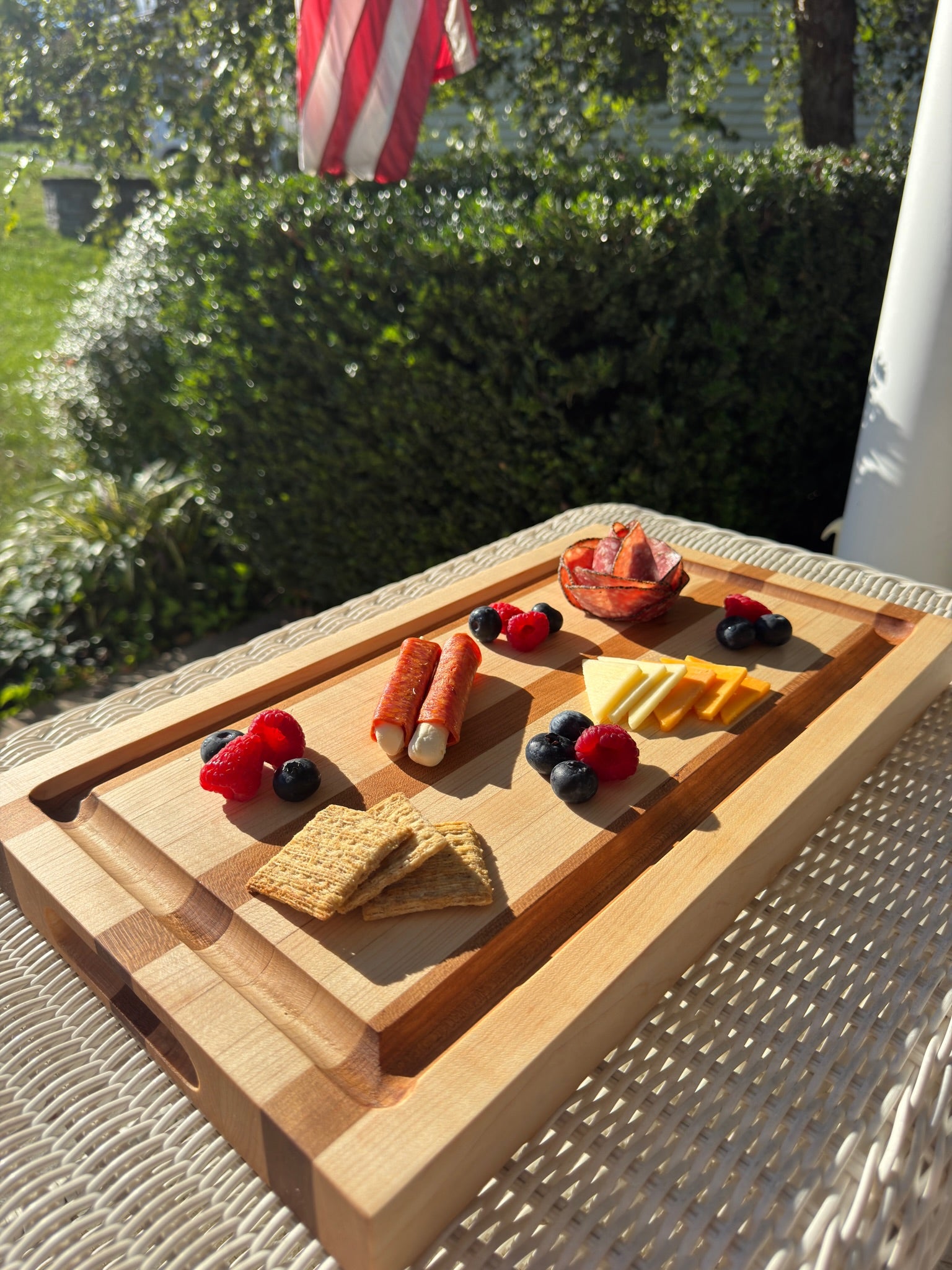 Wooden cutting board with food items on a patio