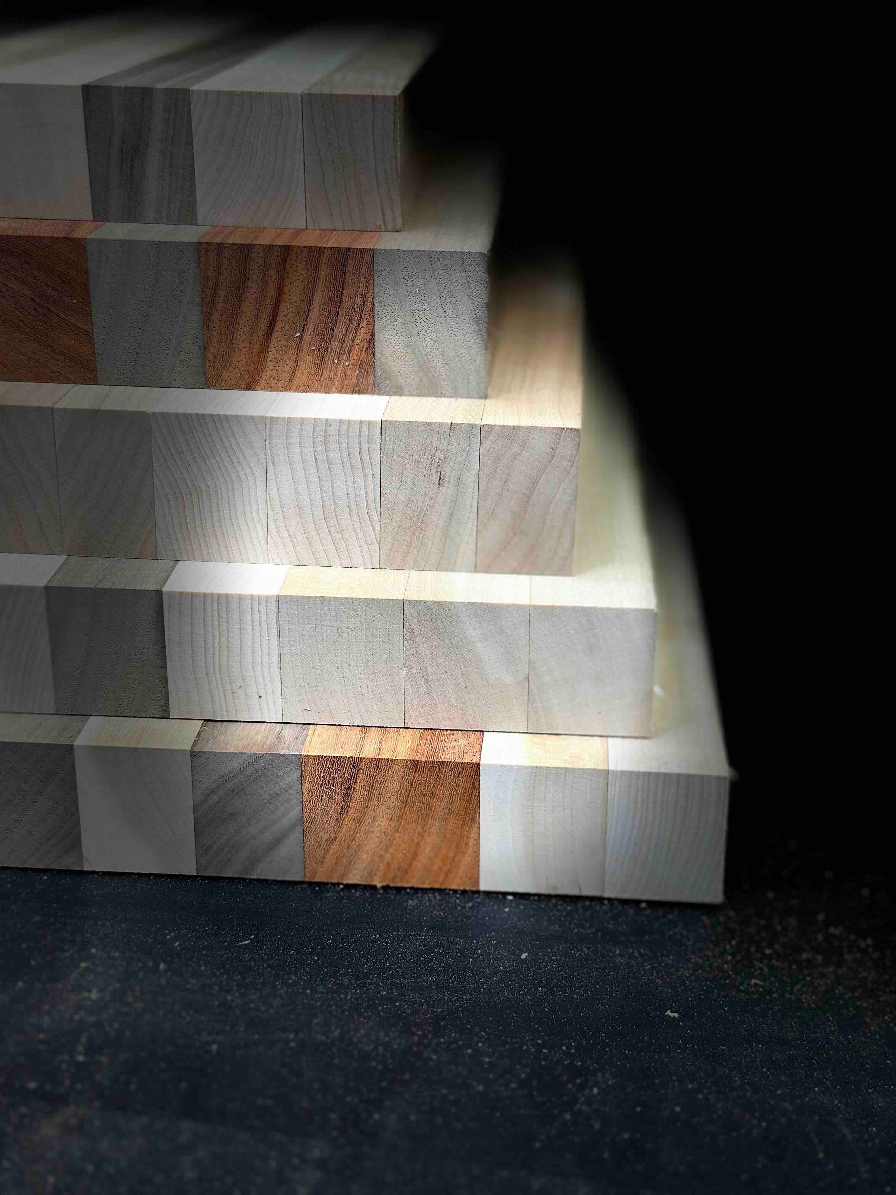 Stack of wooden planks with different wood types on a dark background
