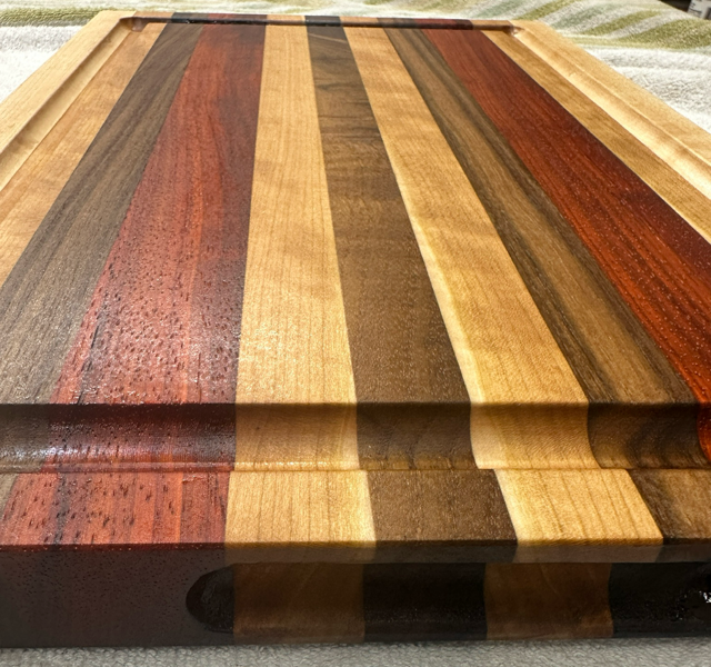 Wooden cutting board with multicolored stripes on a textured surface