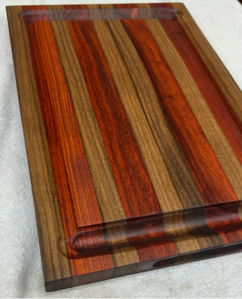 Padauk and Walnut wooden cutting board with a striped pattern on a light gray background
